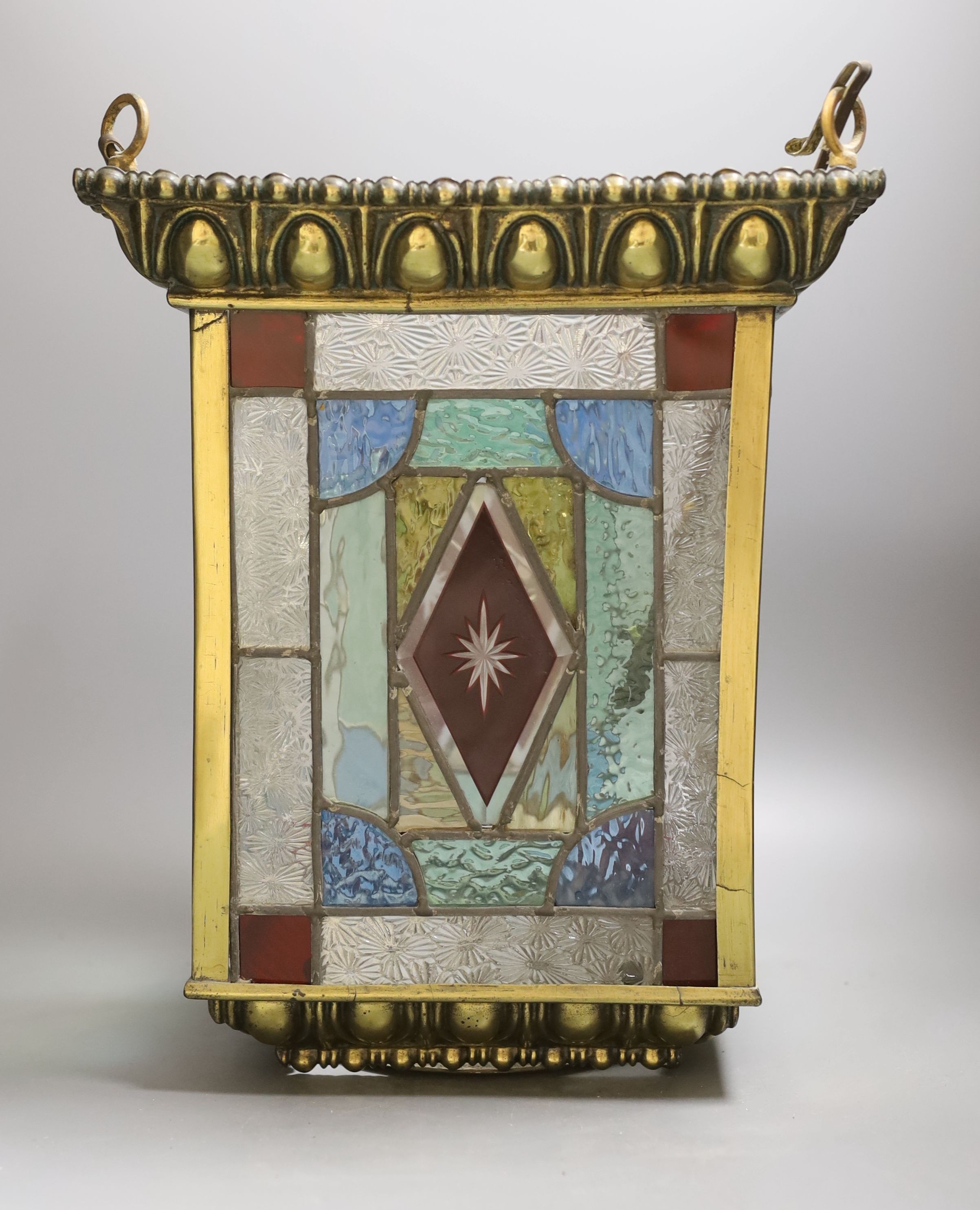 A stained glass and brass hanging hall lantern, 36cm to top of ‘eyes’